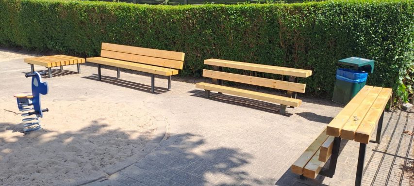 Bänke und ein Müllcontainer in einem Außenbereich mit einer Fitnessstation.