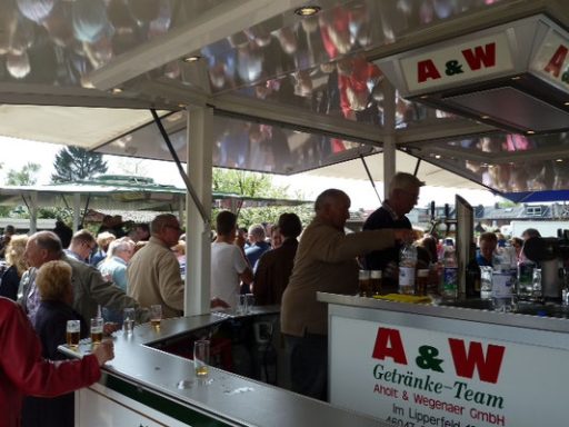 Menschenmenge an einem Außenschalter mit einem Team, das Getränke serviert.